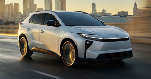 white 2026 Toyota bZ driving on road with skyline In the back